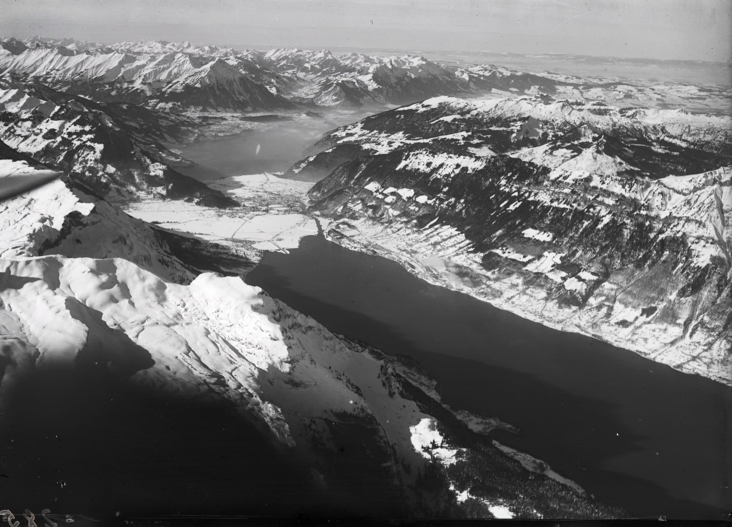 Historisches Luftbild über zwei Alpenseen und verschneite Berge.